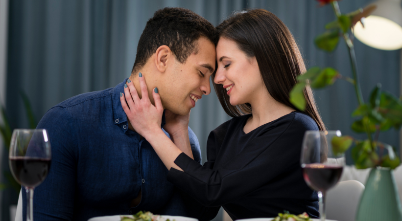 Couple showing desire to partner during romantic dinner date with intimate eye contact and affectionate touch gesture.