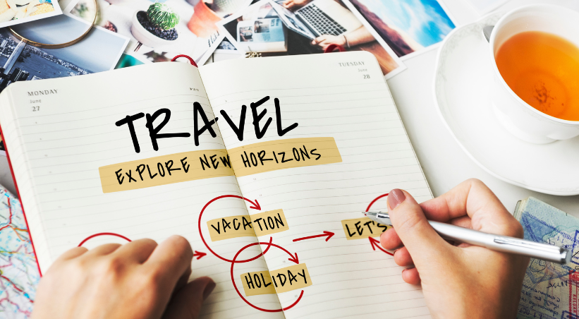 Person planning budget travel vacation in notebook with tea cup and travel photos showing how to travel on a budget.