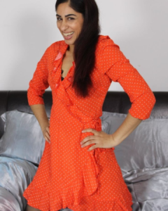 Smiling portrait of a woman wearing an orange polka-dot dress, featured in a blog about Indian Pornstar Names.