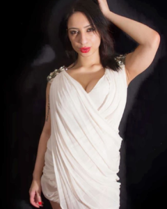 Elegant portrait of a woman in a white draped dress posing against a dark background, featured in a blog about Best Indian Pornstar Names.