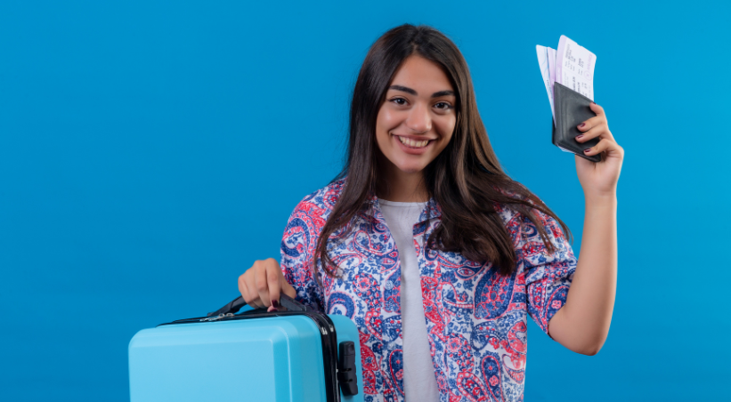 Indian woman traveler holding passport with tickets and blue suitcase ready for visa-free international travel.